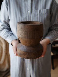 a person holding a wooden bowl in their hands and wearing a blue striped shirt with white stripes