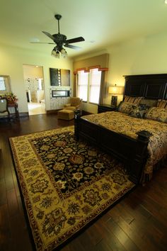 a large bed sitting on top of a wooden floor next to a rug in a bedroom