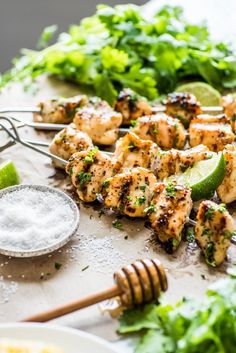 chicken skewers with limes, cilantro and parsley on the side