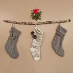 three christmas stockings hanging on a branch with pom - poms