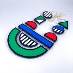 Colour block necklace is a large,fun, bold statement piece. This colourful accessory would look great with any outfit.  The necklace is delicately made with cut out green, blue, white and red acrylic, inserted in a bold black outline and Layered on a clear background. These are linked together using jump rings and has a silver plated curb chain. This has no back clasp, instead you pull over your head.  If you have any questions drop us a line!💌 We are more than happy to help! 😁 To clean your necklace you can simply wipe with a glasses cloth or soft cloth to remove finger marks. Acrylic is a fragile material so please store in a jewellery box to prevent damage.  As ever for safety please keep away from small children. Perspex Jewelry, Plastic Jewellery, Flamingo Necklace, Bright Jewelry, Laser Cut Jewelry, Clear Background, Colorful Accessories, Statement Jewellery, Jewellery Handmade