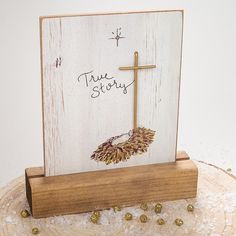 a wooden sign with a cross on it that says true story next to some gold balls