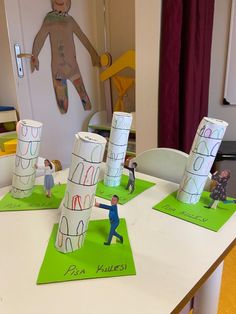 some paper cups are sitting on top of a table with children's drawings in them