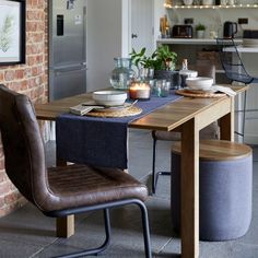 a table with two chairs and plates on it in front of a brick kitchen wall