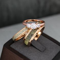 two gold rings with diamonds sitting on top of a wooden display case in front of a gray couch