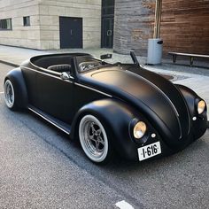 an old black car is parked on the street