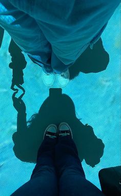 a person standing in front of a swimming pool with their shadow on the water surface