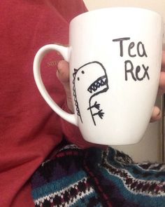 a person holding a coffee cup with a shark drawn on the side and tea rex written on it