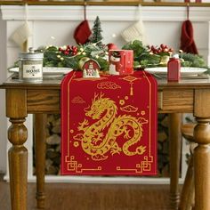 a red and gold dragon table runner sitting on top of a wooden table next to a fireplace