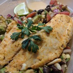 a plate filled with fish and vegetables on top of a table