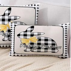 two black and white pillows with yellow bows on them, one has an image of a bunny