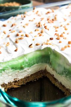 there is a cake with white frosting and green icing on the top, topped with nuts