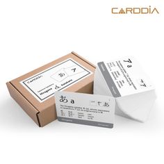 two white business cards sitting next to each other on top of a brown cardboard box