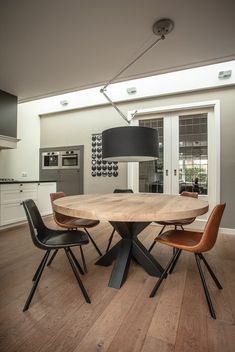 a dining room table with four chairs and a lamp in the middle, on top of a hard wood floor