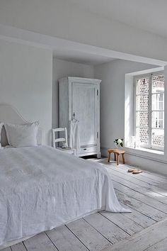 a bedroom with white walls and wooden floors