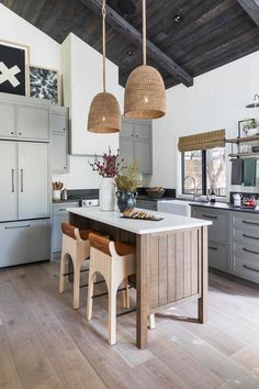 a kitchen with two pendant lights hanging from the ceiling and an island in the middle