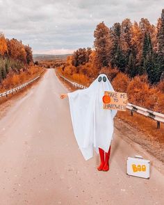 a person in red boots and a ghost costume is standing on the side of a road