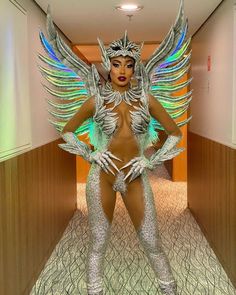 a woman with wings on her body standing in an elevator way wearing silver and green glitters