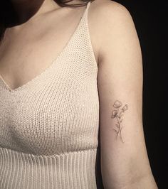 a woman with a small flower tattoo on her left arm and right arm behind her back