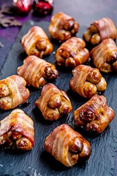 some bacon wrapped up in pieces on a black board with other food items around it