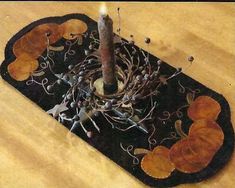 a candle is sitting on top of a black mat with leaves and twigs around it