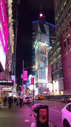 a city street at night with neon lights and tall buildings