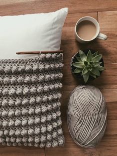 there is a crochet afghan next to a cup of coffee and a ball of yarn