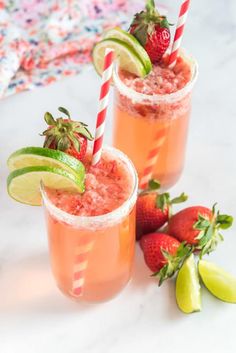 two glasses filled with strawberry margaritas and limeade garnished with strawberries