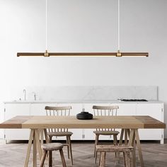 a wooden table and chairs in a white kitchen with marble counter tops on the island