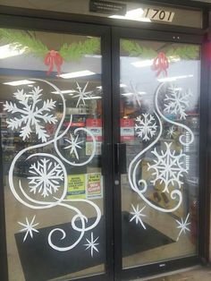 a store front with frosting on the glass and snowflakes hanging from it's doors