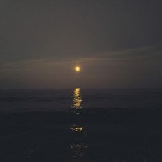 the moon is shining over the ocean at night