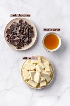 ingredients for chocolate fudge on a white marble counter top, including tofu, dark chocolate and maple syrup