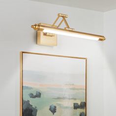 a painting is hanging on the wall next to a light fixture in a white room