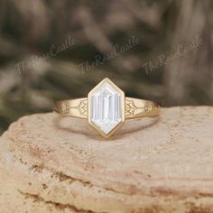 a gold ring with an emerald cut diamond in the center on top of a rock