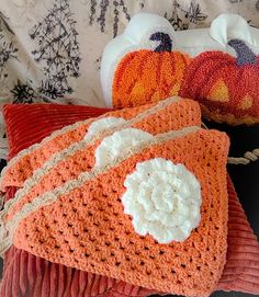 three crocheted pumpkin pillows on a bed