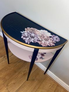 a table with flowers painted on it and gold trim around the edge, sitting against a wall