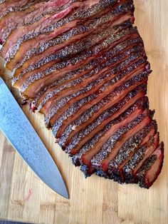 a large piece of meat sitting on top of a cutting board next to a knife