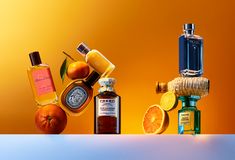 an assortment of different types of perfumes and oranges on a white table with yellow background