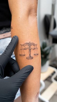 a person with a tattoo on their arm holding up a scale and weight scales tattooed on the leg