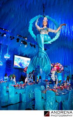 a woman in a blue dress standing on top of a table covered in ice decorations