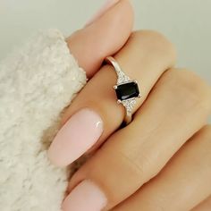 a woman's hand with pink and white nails holding an engagement ring on her finger