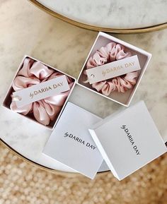 three small pink scrunffles in a box on a marble table with name tags