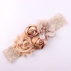 the headband has three flowers and lace on it, along with an ivory flower