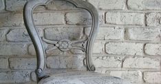 an old chair is upholstered against a brick wall with newspaper pages on it