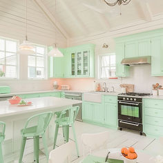 a kitchen with mint green cabinets and white counter tops, an island in the middle