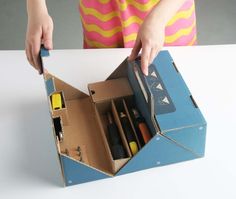 a person opening an open cardboard box with tools in it on a white table top