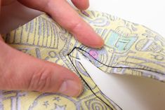 a person is sewing on a piece of fabric with their thumb in the middle of it