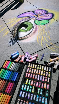 the sidewalk is covered in chalk and crayons, with an eye drawn on it