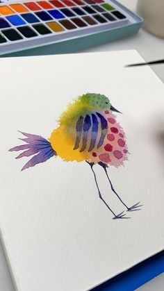 a watercolor painting of a colorful bird on white paper