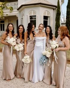 a group of women standing next to each other in front of a white and gray house